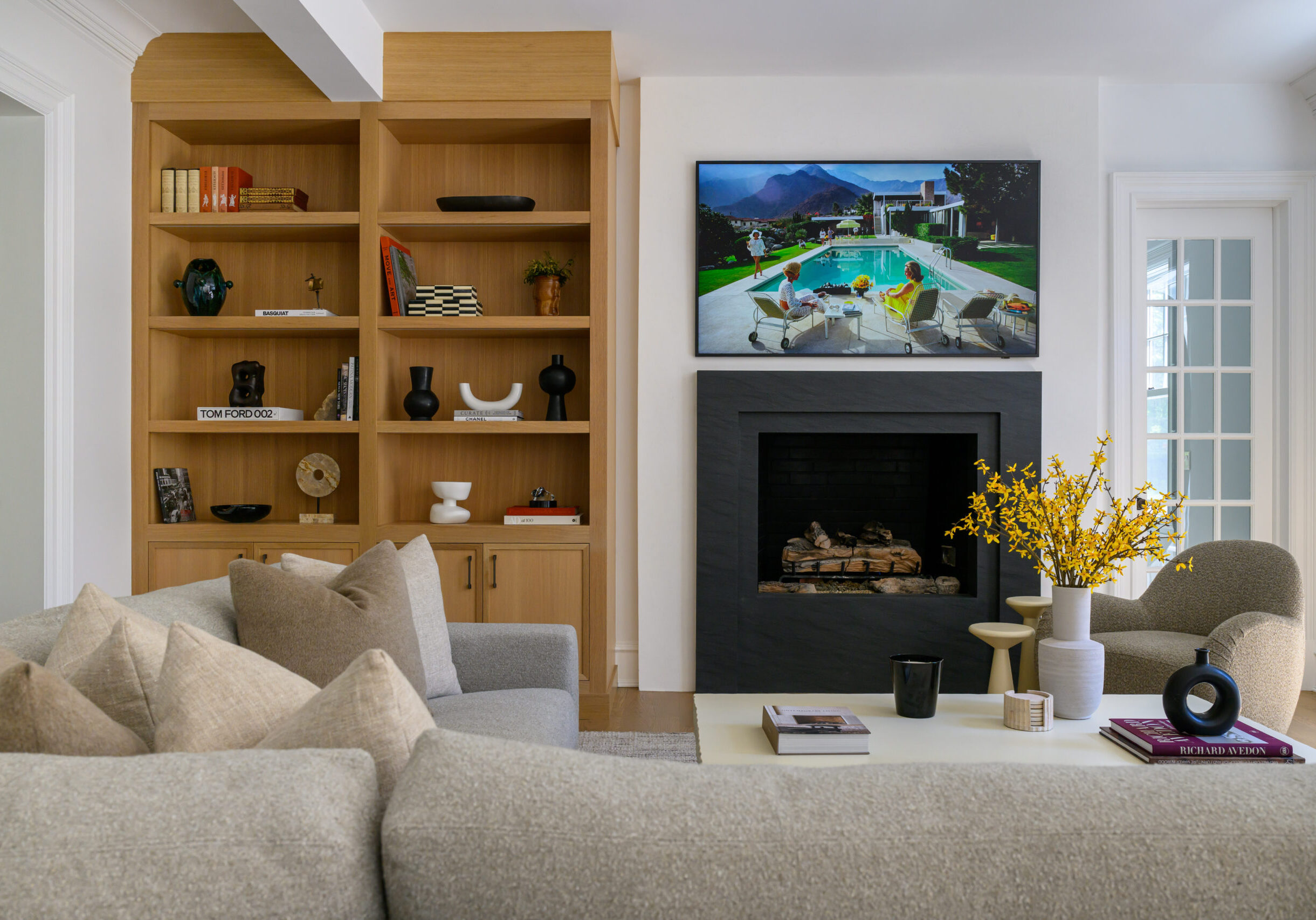 Custom living room built-in shelving and a sleek fireplace surround create a warm focal point in this Riverside home, blending natural wood tones with curated objects and modern art.